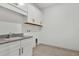 Well-lit laundry area with a sink, ample cabinet space, and neutral tile flooring at 17920 Palmiste Dr, Bradenton, FL 34202
