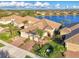 Aerial view of the home with a lake view, tile roof, manicured lawn, and lush landscaping at 21620 Avon Park Ct, Venice, FL 34293