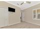 Cozy bedroom with neutral walls, carpet, a ceiling fan, closet, and TV at 21620 Avon Park Ct, Venice, FL 34293