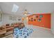 Open living area featuring an orange accent wall, skylights, tile flooring, and comfortable leather seating at 2551 W Burr Oak Ct, Sarasota, FL 34232