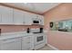 Bright kitchen featuring white cabinets, appliances, and a pass-through to the living area at 1626 Stickney Point Rd # 26-102, Sarasota, FL 34231