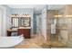 This bathroom features a soaking tub, vanity and frameless glass shower, with neutral stone tile at 1810 Lincoln Dr, Sarasota, FL 34236