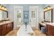 Luxurious bathroom with a soaking tub, wood cabinets, and dual doors with views of the backyard at 1810 Lincoln Dr, Sarasota, FL 34236