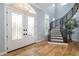 Bright foyer featuring wood floors, a decorative staircase, and glass paneled doors at 1810 Lincoln Dr, Sarasota, FL 34236