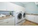 Well-lit laundry room with two white front loading washers and dryers, cabinets, and a folding counter at 1810 Lincoln Dr, Sarasota, FL 34236