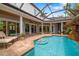 Relaxing screened-in pool with a stone grotto waterfall, surrounded by lush landscaping and lounge seating at 1810 Lincoln Dr, Sarasota, FL 34236