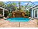Screened pool with rock waterfall feature and tropical landscaping in backyard at 1810 Lincoln Dr, Sarasota, FL 34236