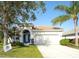 Charming single-story home featuring a well-manicured lawn, blue door, tile roof, and a two-car garage at 236 Golden Harbour Trl, Bradenton, FL 34212