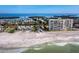 Overhead view of beachfront properties, sandy beach and gentle waves, offering a blend of relaxation and residential comfort at 605 Sutton Pl # 205, Longboat Key, FL 34228