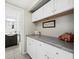 Bright laundry room featuring white cabinets, gray countertops, and a view of the bathroom at 605 Sutton Pl # 205, Longboat Key, FL 34228