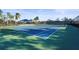 A community tennis court sits ready for a match with pristine blue and green surfacing and manicured landscaping at 11422 Griffith Park Ter, Bradenton, FL 34211