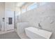 Elegant bathroom with a modern soaking tub, a spacious walk-in shower, and marble tile at 3939 Higel Ave, Sarasota, FL 34242