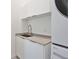 Modern laundry room featuring gray countertops and white cabinets at 3939 Higel Ave, Sarasota, FL 34242