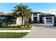 Beautiful two-story home with lush landscaping, palm trees, and a brick driveway at 5305 Brookgrove Dr, Sarasota, FL 34238