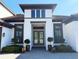 A close up shot of a white two-story home with a beautiful dark wooden door and decorative landscaping at 5305 Brookgrove Dr, Sarasota, FL 34238
