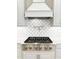 Close up of a gourmet gas range with brass knobs and diamond patterned backsplash at 5305 Brookgrove Dr, Sarasota, FL 34238