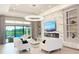 Bright, open-concept living room with modern chandelier, fireplace, and access to outdoor pool at 5305 Brookgrove Dr, Sarasota, FL 34238