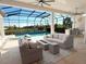 Screened-in outdoor living space featuring comfortable seating, a fire pit, an outdoor kitchen, and a stunning pool view at 5305 Brookgrove Dr, Sarasota, FL 34238