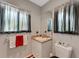 Cozy bathroom with a neutral vanity, red and white towel and decorative black out curtains at 5376 Shadow Lawn Dr, Sarasota, FL 34242
