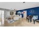 Stylish living room with blue accent wall featuring a piano and lots of natural light at 5376 Shadow Lawn Dr, Sarasota, FL 34242