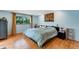 Comfortable bedroom features wooden floors, natural light, and an eye-catching abstract painting at 5402 Shadow Lawn Dr, Sarasota, FL 34242