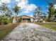 Quaint single-story home featuring a gravel driveway and verdant surroundings under a bright sky at 5645 Churchill Downs Rd, Sarasota, FL 34241
