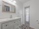 Bathroom featuring vanity with sink, mirror, unique tile floors, and door access to exterior at 625 Ennis Nw Ter, Port Charlotte, FL 33952