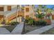 Exterior view of a two-story condo featuring wood accents and lush tropical landscaping at 144 Wild Palm Dr, Bradenton, FL 34210