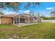 View of the home's backyard featuring a screened-in patio with a pool and spacious green lawn at 1577 Taggard Rd, North Port, FL 34288