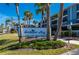 Sandpiper Key condo community entrance with lush landscaping and bright blue buildings against a clear sky at 1751 Beach Rd # 404, Englewood, FL 34223