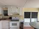 The kitchen with white cabinets and appliances, provides an eat-in breakfast area with a view at 2601 Gulf N Dr # B16, Bradenton Beach, FL 34217