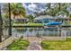 Waterfront home with boat, dock, and walkway surrounded by manicured lawn and lush landscaping at 4708 Clipper Dr, Bradenton, FL 34208