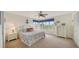 Light-filled primary bedroom with cozy decor, a ceiling fan, neutral carpet, and a large window at 653 Cedars Ct, Longboat Key, FL 34228