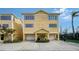 Exterior of a two-story, yellow townhouse with two garage doors, and a landscaped entrance at 653 Cedars Ct, Longboat Key, FL 34228