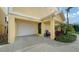 Close up of a one-car garage featuring a covered entry, a chair, and beautiful landscaping at 653 Cedars Ct, Longboat Key, FL 34228