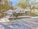 Charming gray home features covered parking, screened porch and mature landscaping on a sunny day at 514 Riverside E Dr, Bradenton, FL 34208