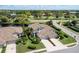 An aerial view of a tan-roofed home nestled among lush landscaping, ponds, and a golf course at 8737 Pebble Creek Ln, Sarasota, FL 34238