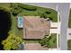 Aerial view of a home featuring a tile roof, screened-in pool, well-manicured landscaping, and pond at 8737 Pebble Creek Ln, Sarasota, FL 34238