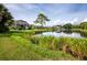 Beautiful backyard view of homes lining a serene lake, complete with green lawns and mature trees at 8737 Pebble Creek Ln, Sarasota, FL 34238