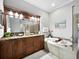 Elegant Primary bathroom featuring a luxurious soaking tub, dual sinks, and wood cabinets for a spa-like experience at 8737 Pebble Creek Ln, Sarasota, FL 34238