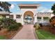 Charming arched entrance with stone walkway leading to a gated community, enhanced by verdant landscaping at 8737 Pebble Creek Ln, Sarasota, FL 34238