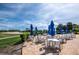 Outdoor patio with tables and blue umbrellas with a golf course in the background at 8737 Pebble Creek Ln, Sarasota, FL 34238