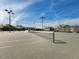 A well-maintained tennis court featuring a new net and lights is set against a vibrant blue sky at 8737 Pebble Creek Ln, Sarasota, FL 34238