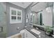 Gray bathroom featuring a white toilet and vanity and large mirror with decorative lighting at 11432 Savannah Lakes Dr, Parrish, FL 34219