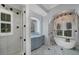Elegant bathroom featuring a soaking tub, decorative windows, and gray cabinetry at 11432 Savannah Lakes Dr, Parrish, FL 34219