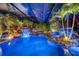 Beautiful enclosed pool with rock features, waterfalls, and lush landscaping with lighting at 11432 Savannah Lakes Dr, Parrish, FL 34219