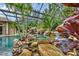 Screened pool with rock features, waterfalls, spa, and lush tropical landscaping at 11432 Savannah Lakes Dr, Parrish, FL 34219