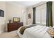 Bright bedroom featuring a white bedspread, wooden dresser, and soothing green curtains at 130 Riviera Dunes Way # 1104, Palmetto, FL 34221