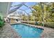 Sparkling screened-in pool surrounded by lush landscaping, patio seating, and a clear blue sky at 327 Hernando Ave, Sarasota, FL 34243