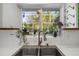 Kitchen sink overlooking backyard features stainless steel fixtures, white tiled backsplash, and flowers at 327 Hernando Ave, Sarasota, FL 34243